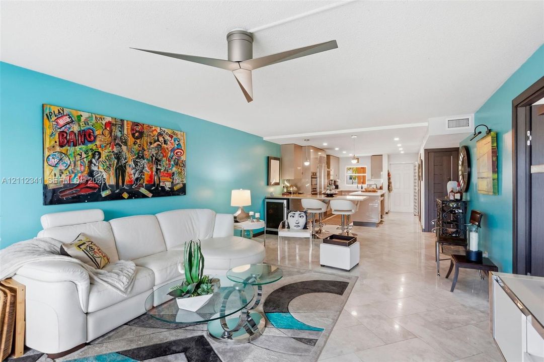 Open-concept living space featuring high-gloss tile flooring, a modern three-blade ceiling fan, and recessed lighting