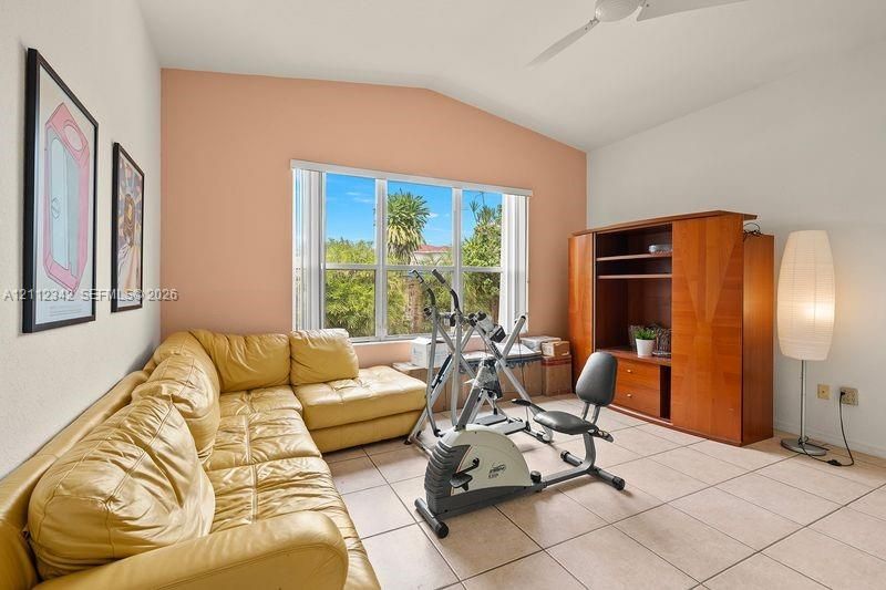 Vaulted ceiling, ceramic tile flooring, built-in wooden cabinetry, and large multi-pane windows