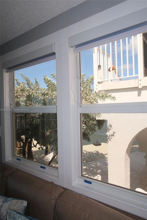 Dual white-framed double-hung windows with integrated roller shades and sand-finish exterior trim