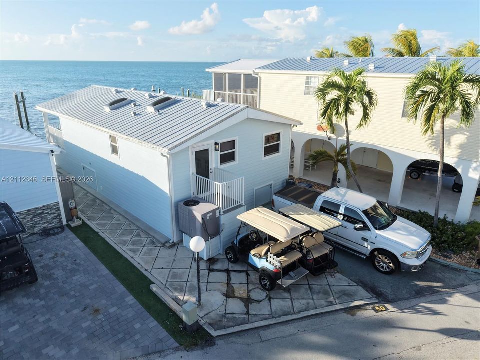 Waterfront property exterior featuring metal roofing, skylights, horizontal siding, and a paved parking area