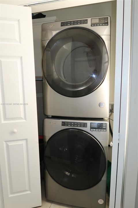 Stacked front-load metallic-finish laundry set housed within a dedicated closet