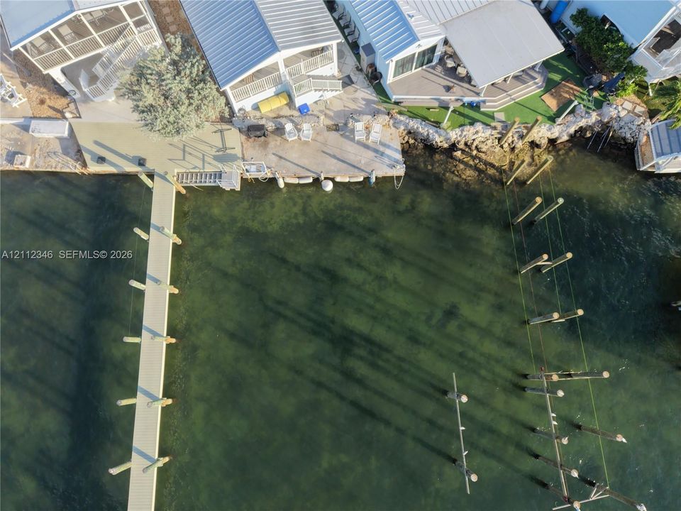 Waterfront property featuring a private boat dock, extended pier, bulkhead hardscaping, and metal roofing