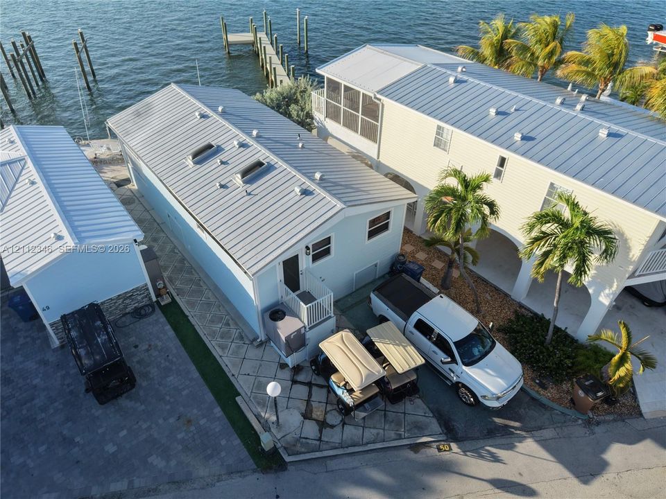Waterfront property featuring a metal roof, dual skylights, paved exterior grounds, and a private dock