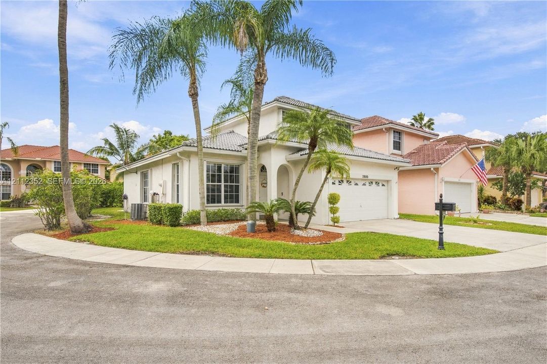 Two-story stucco exterior featuring a tiled roof, arched entryway, multi-pane windows, and an attached two-car garage