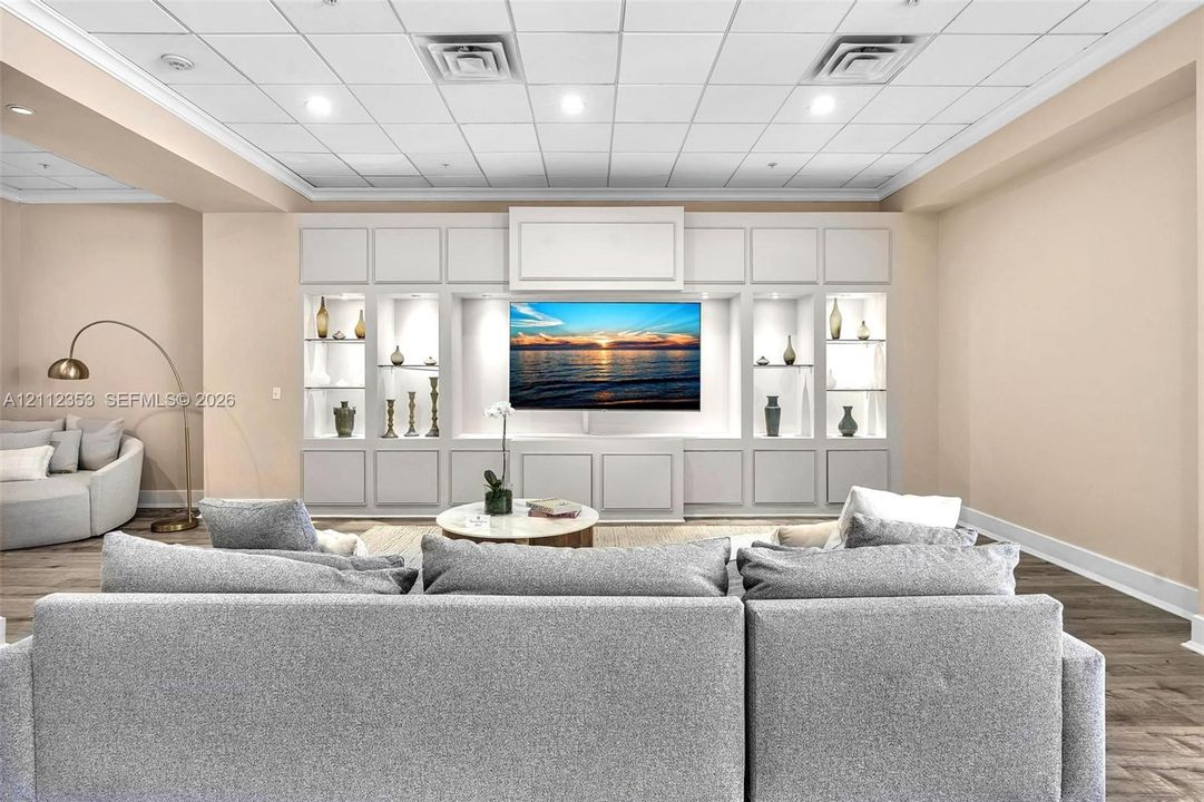 Custom floor-to-ceiling built-in cabinetry with integrated shelving and recessed lighting, wood-finish flooring, and drop ceiling