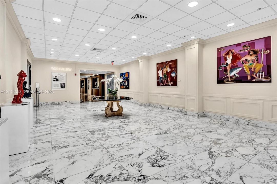 Expansive lobby featuring polished stone flooring, recessed ceiling lighting, and wainscoting detail