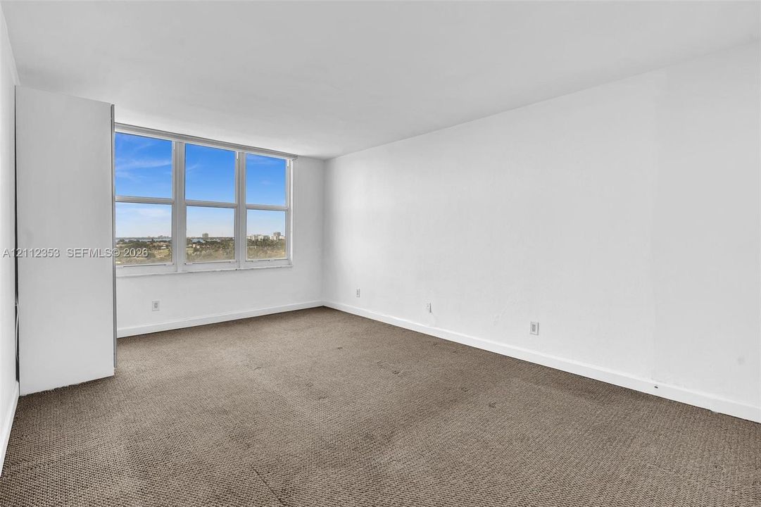 Interior space featuring neutral wall-to-wall carpeting, large multi-pane windows, and built-in closet storage