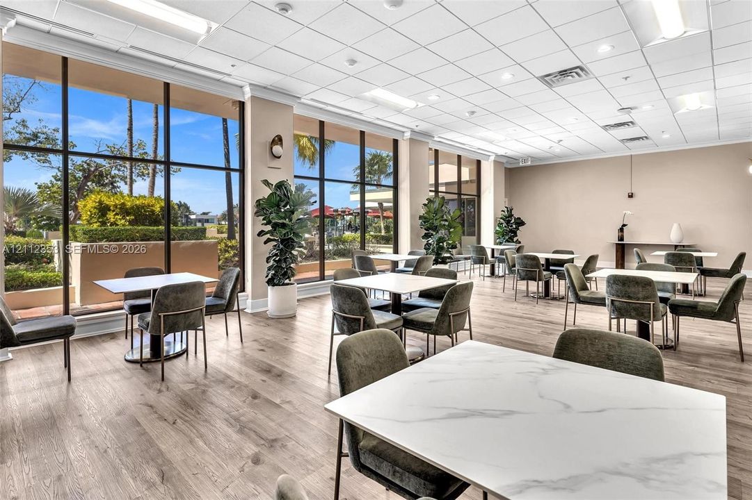 Expansive interior space featuring floor-to-ceiling windows, wood-finish flooring, and a drop ceiling with recessed lighting