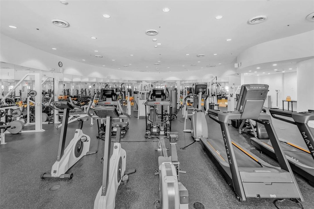 Fitness center featuring rubber flooring, recessed ceiling lighting, and wall-to-wall mirrors