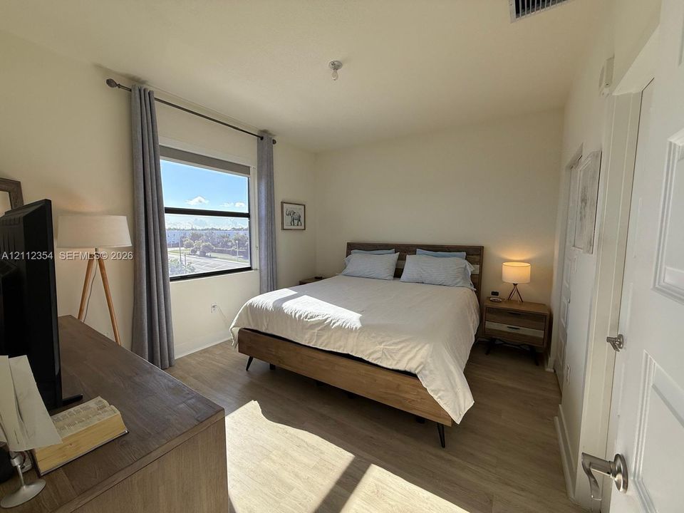 Neutral walls, wood-finish flooring, and a single-pane window featuring exterior cityscape scenery