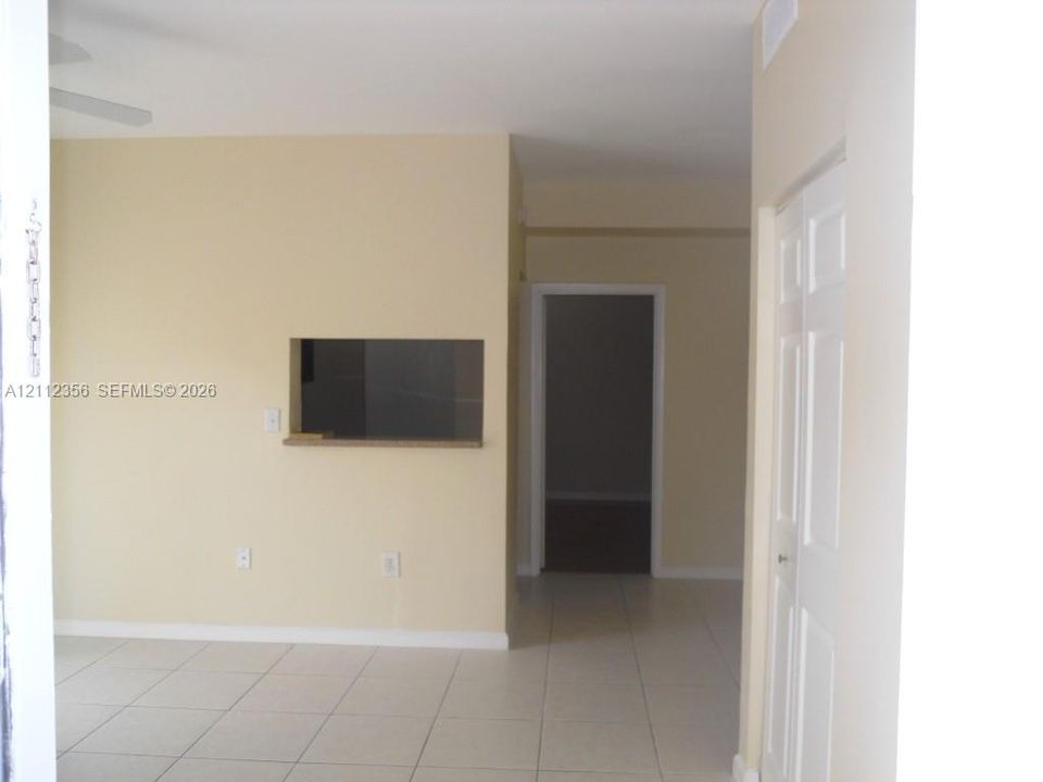 Neutral wall paint, light-toned ceramic tile flooring, and interior pass-through window with a stone-finish ledge