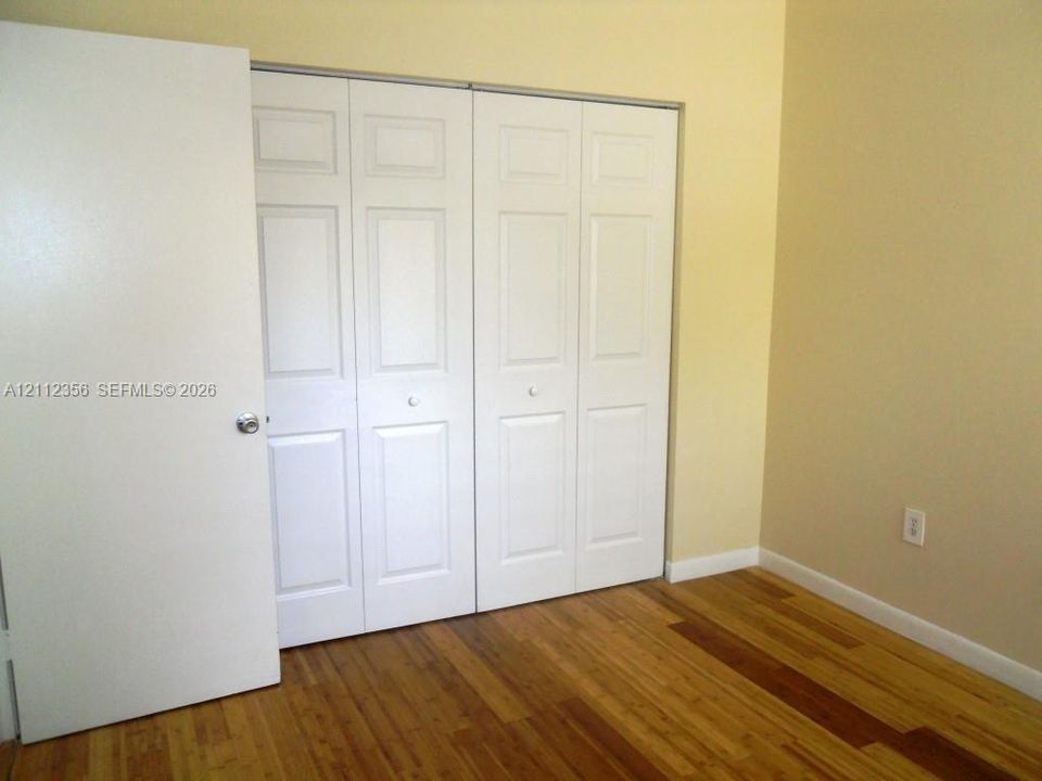 Wood-finish flooring paired with white four-panel bi-fold closet doors and a matching white swinging door