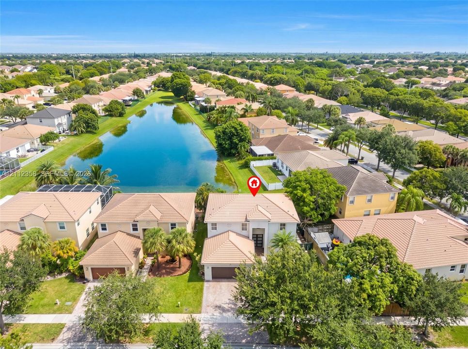 Aerial perspective featuring a two-story residence with a concrete tile roof, a multi-car garage, and proximity to a water feature