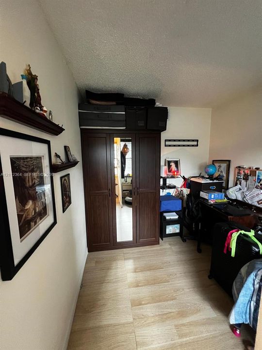 Wood-finish flooring throughout, featuring a built-in dark wood cabinetry unit with a central mirrored panel