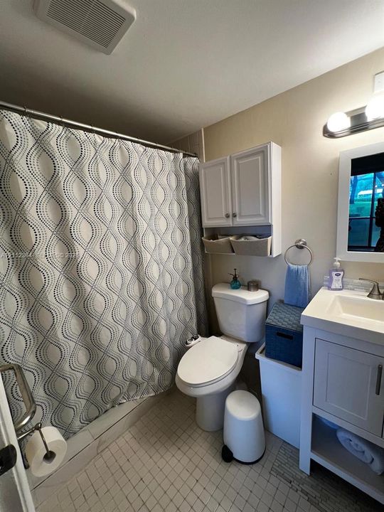 Bathroom featuring a vanity with integrated sink, wall-mounted upper cabinetry, tub-shower combination, tiled flooring, and multi-bulb light fixture