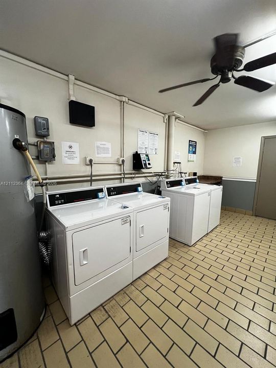 Utility area featuring ceramic tile flooring, two commercial-grade laundry sets, and a ceiling-mounted fan