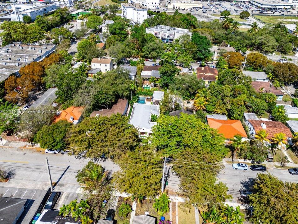 Aerial view of a residential property featuring a swimming pool, mature canopy trees, and an asphalt driveway