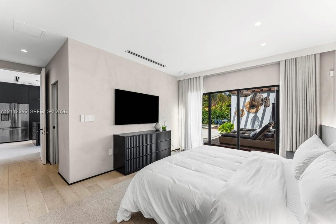 Neutral-toned walls, wood-finish flooring, recessed lighting, and expansive floor-to-ceiling sliding glass doors