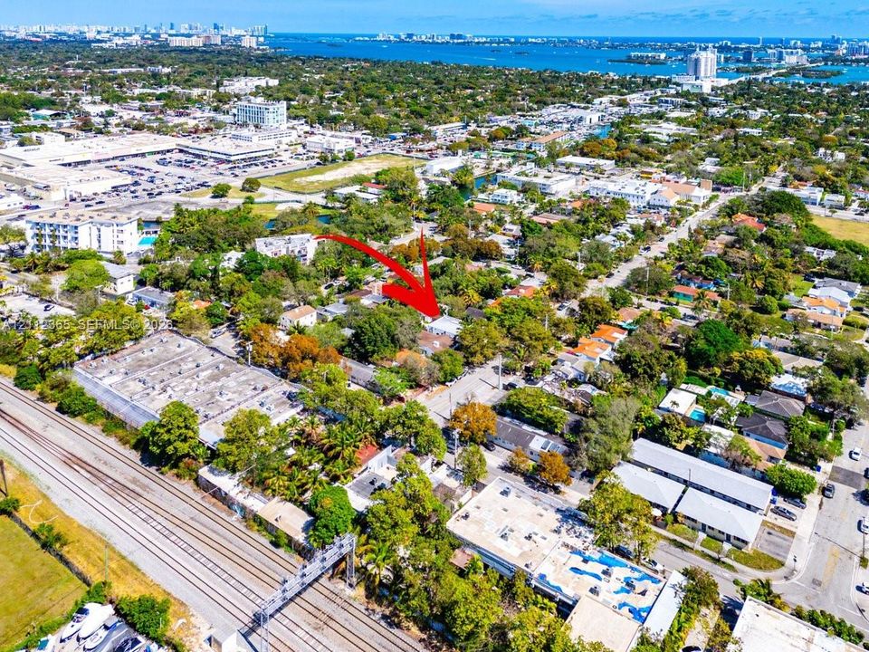 Aerial perspective of residential parcel featuring mature trees, surrounding urban landscape, and coastal water backdrop
