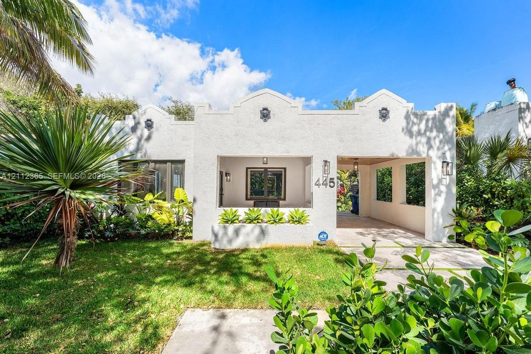 Mission Revival exterior featuring a smooth stucco façade, parapet roofline with decorative medallions, built-in concrete planter, and integrated covered entrance