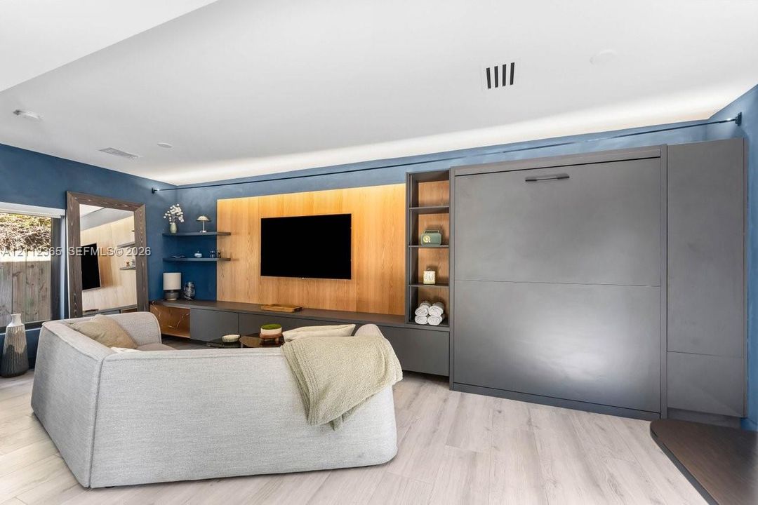Custom built-in cabinetry with integrated Murphy bed, wood-finish flooring, recessed lighting, and light wood accent wall