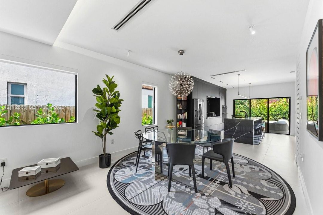 Open-concept interior featuring large-format tile flooring, a kitchen island with dark stone-finish surfacing, recessed lighting, and expansive sliding glass doors