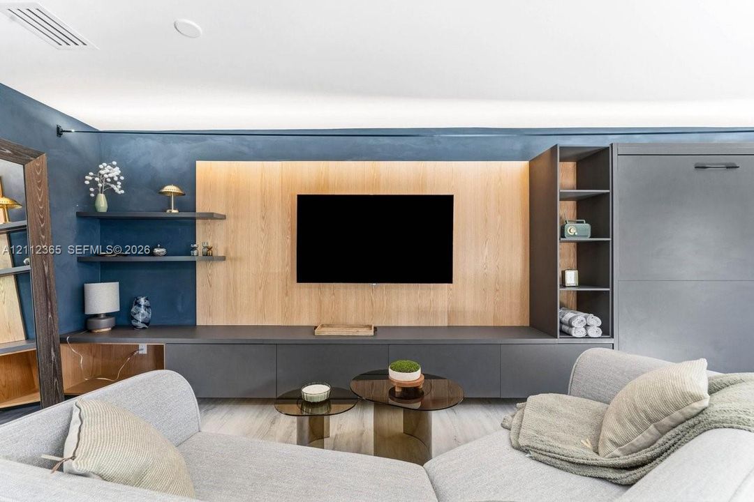 Custom-built wall unit featuring dark grey cabinetry, integrated wood-finish paneling, open shelving, and hidden storage