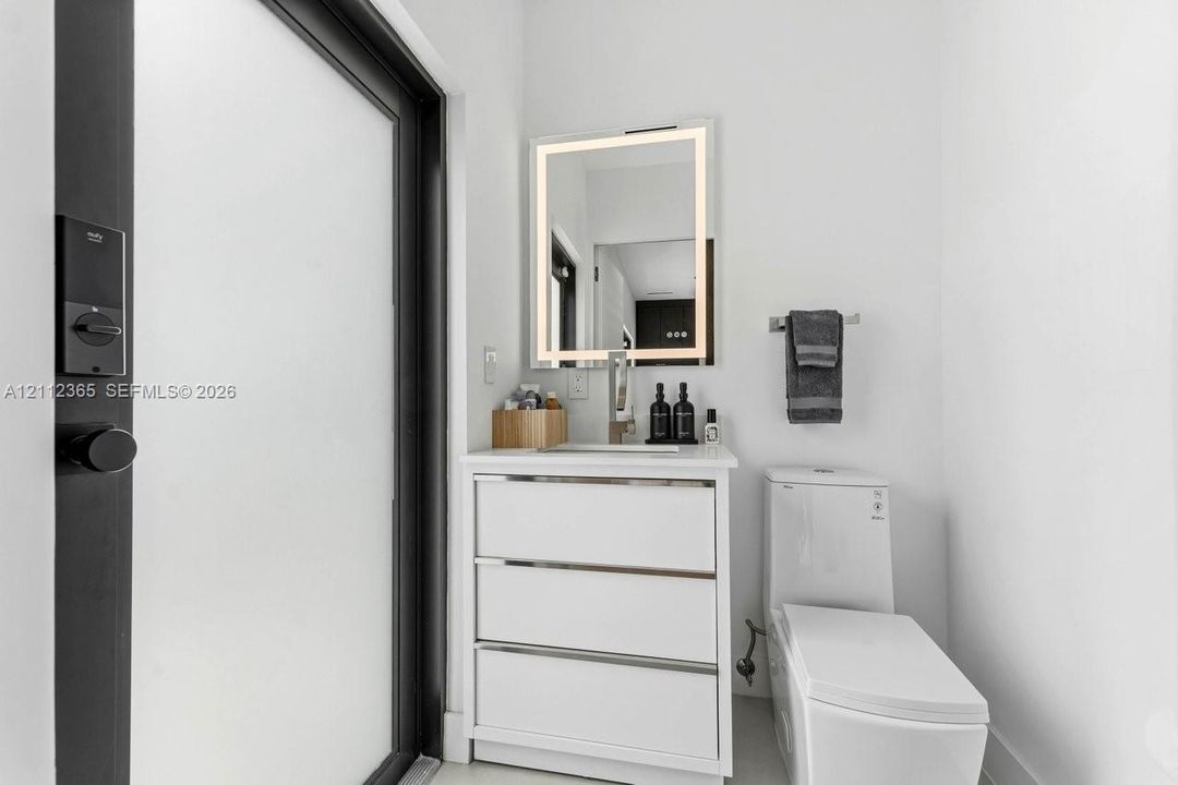 Modern vanity featuring white cabinetry, metallic hardware, and a solid surface countertop