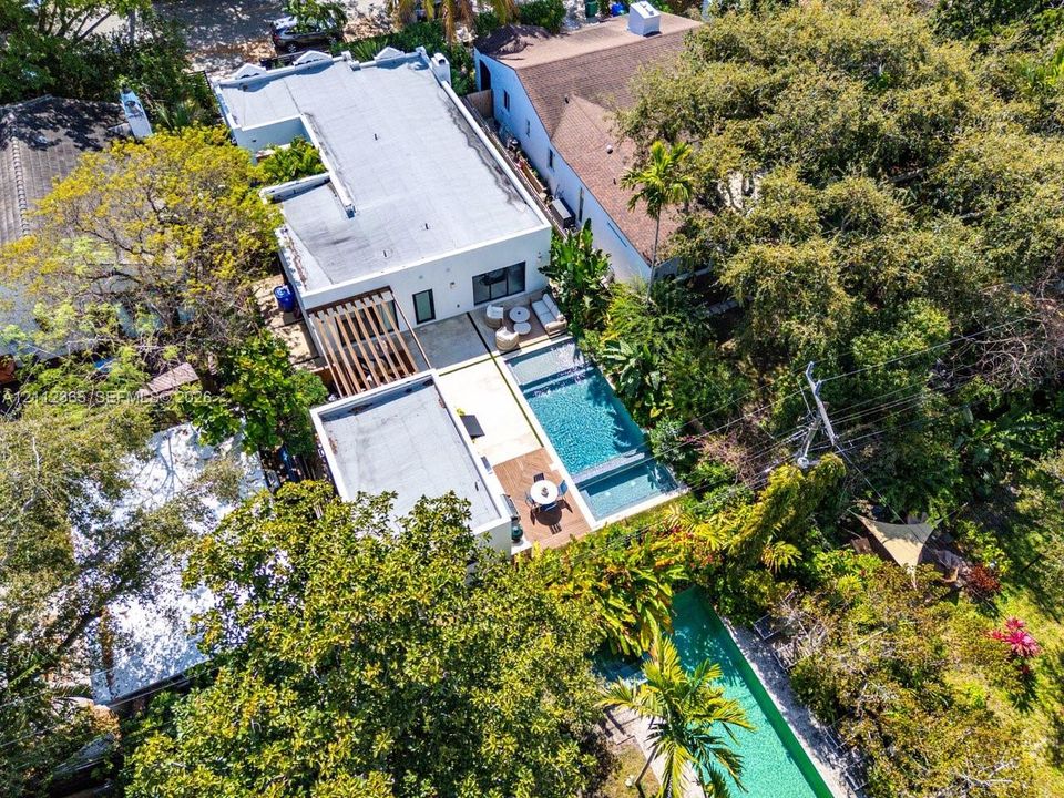 Aerial perspective of property featuring a flat-roofed architectural structure, a rectangular swimming pool, a custom pergola, and paved hardscaping