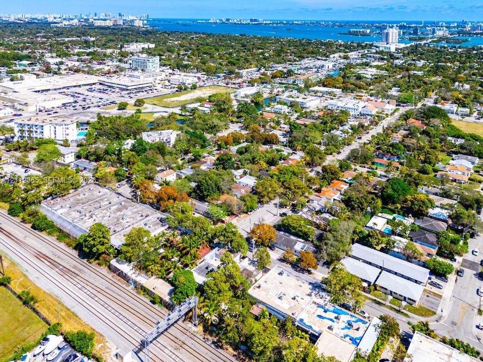Aerial perspective of coastal residential area featuring mature canopy trees, proximity to metropolitan commercial infrastructure, and waterfront reach