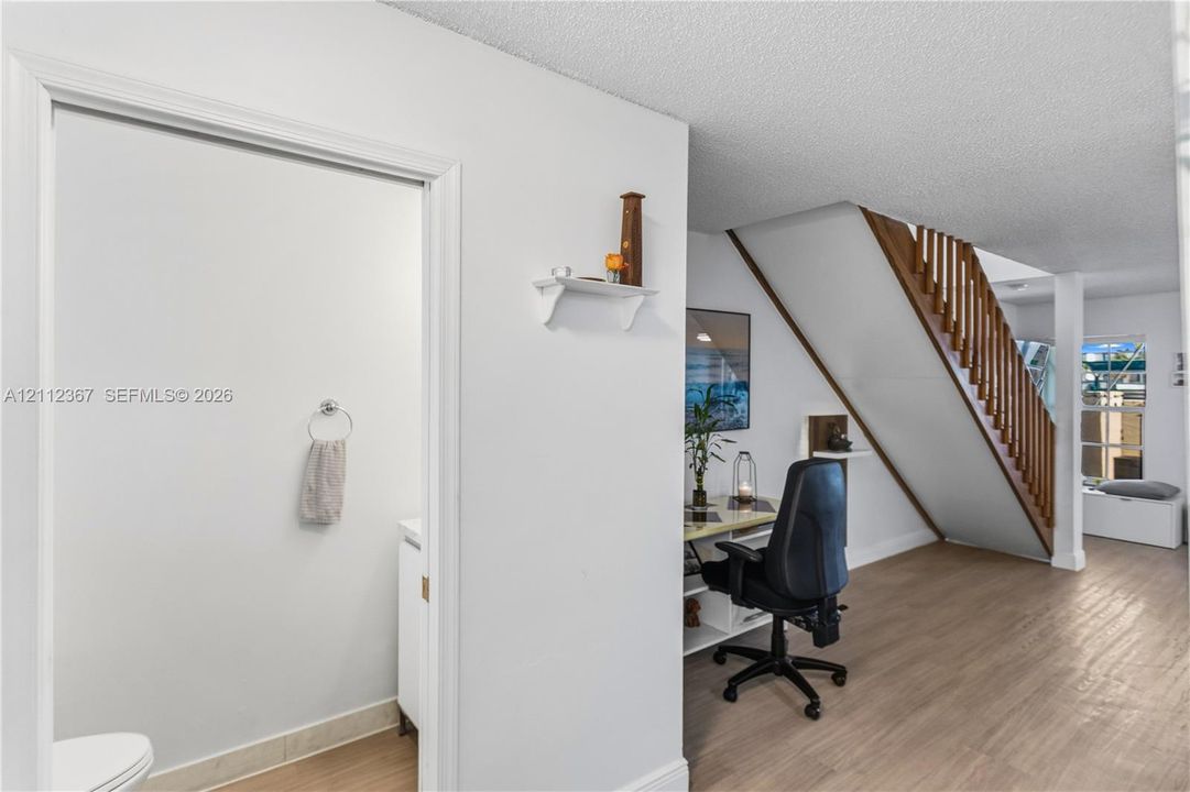 Wood-finish flooring, open-riser staircase with wood balusters, and crisp white interior paint