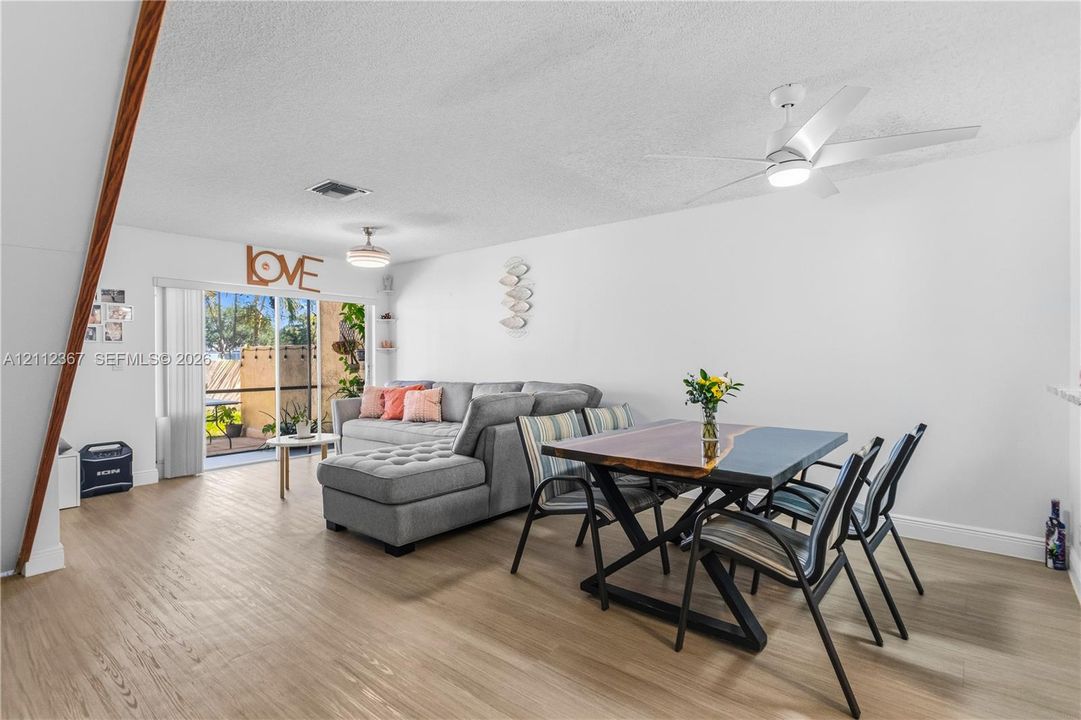 Wood-finish flooring, ceiling-mounted fan with integrated lighting, and sliding glass doors