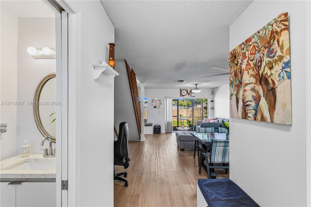 Interior space featuring wood-finish flooring, a bathroom with an oval mirror and vanity, a staircase with wooden railings, and sliding glass doors