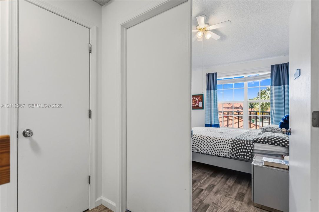 Room interior featuring wood-finish flooring, a multi-pane window, and an attached ceiling fan with light fixture