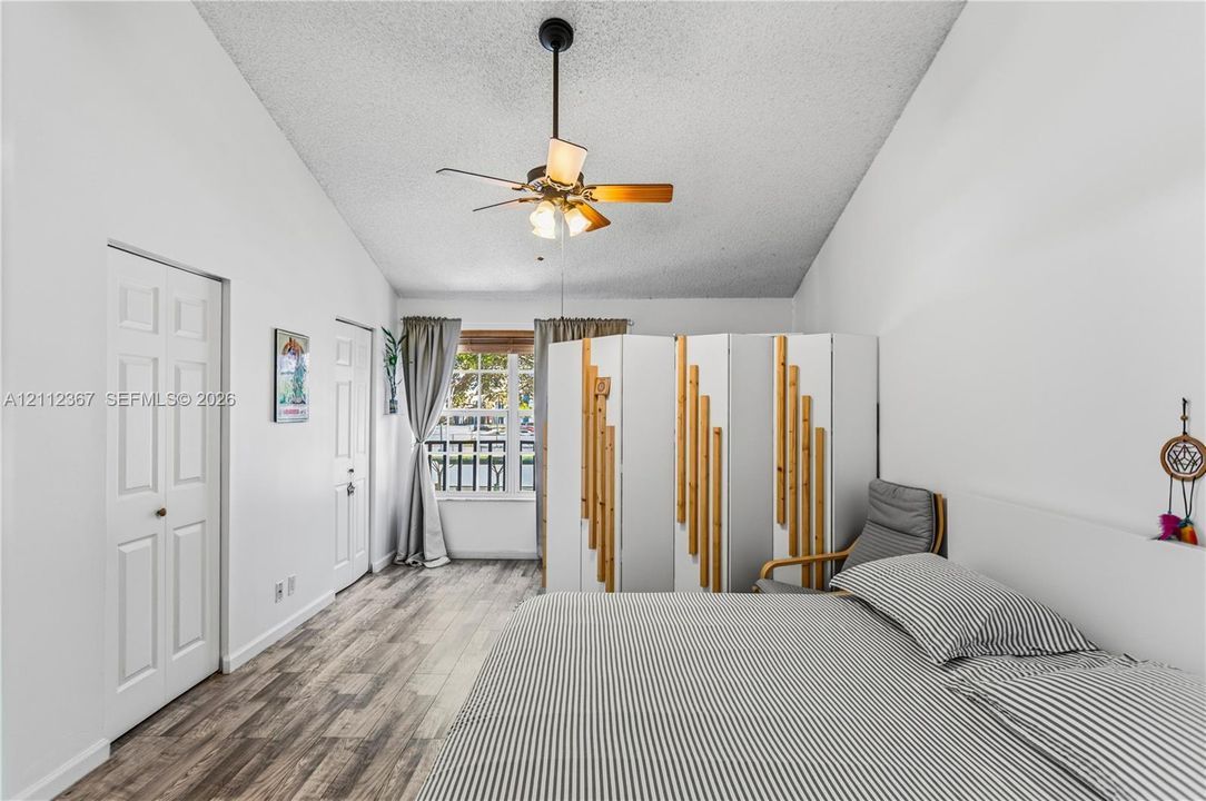 Vaulted ceilings, wood-finish flooring, two-panel interior doors, and a ceiling-mounted light fixture