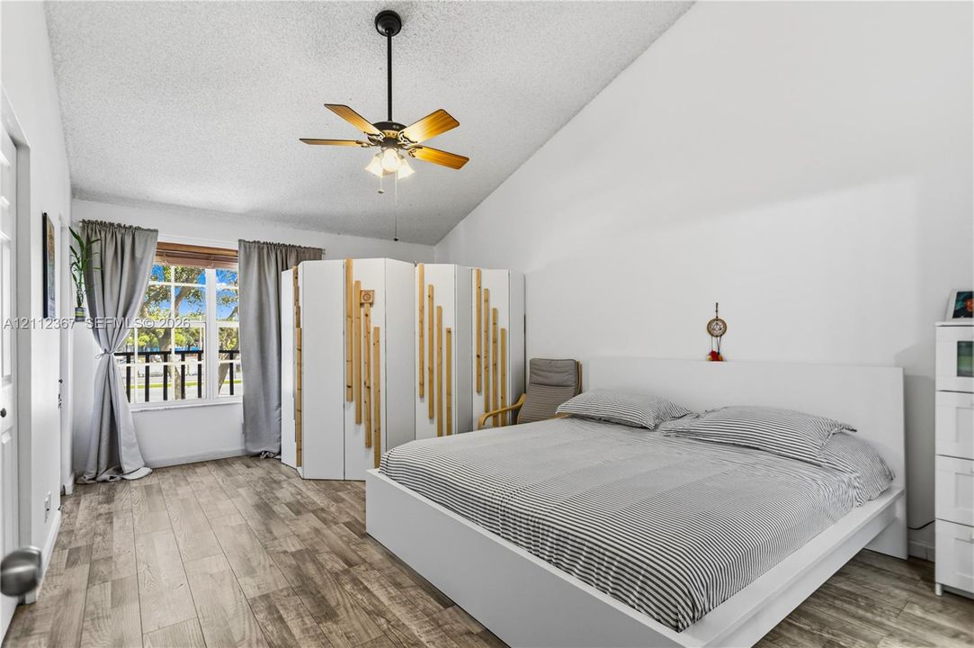 Vaulted ceilings, wood-finish flooring, and a central ceiling fan with integrated light fixture