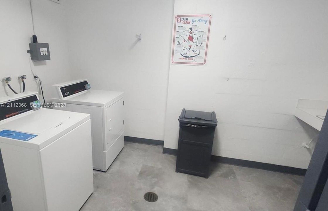 Utility room featuring large-format tile flooring, dedicated washer and dryer hookups, and a built-in wall-mounted sink basin
