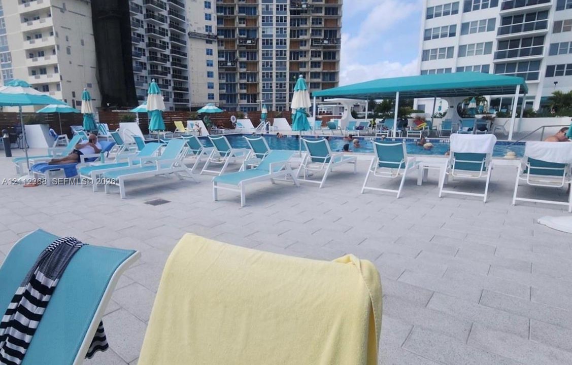 Swimming pool featuring stone-paver decking and a covered shaded patio area