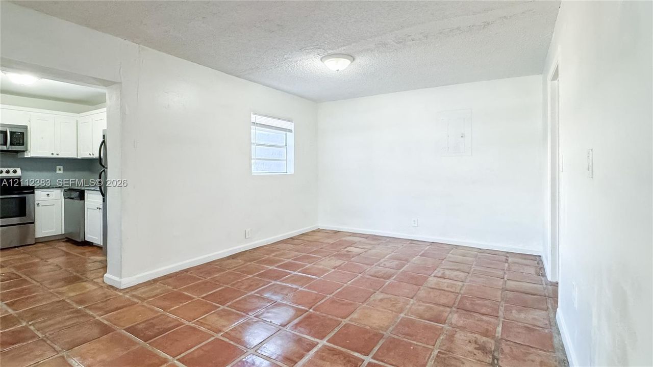 Interior space featuring ceramic tile flooring, a flush-mount ceiling light fixture, and a window with blinds