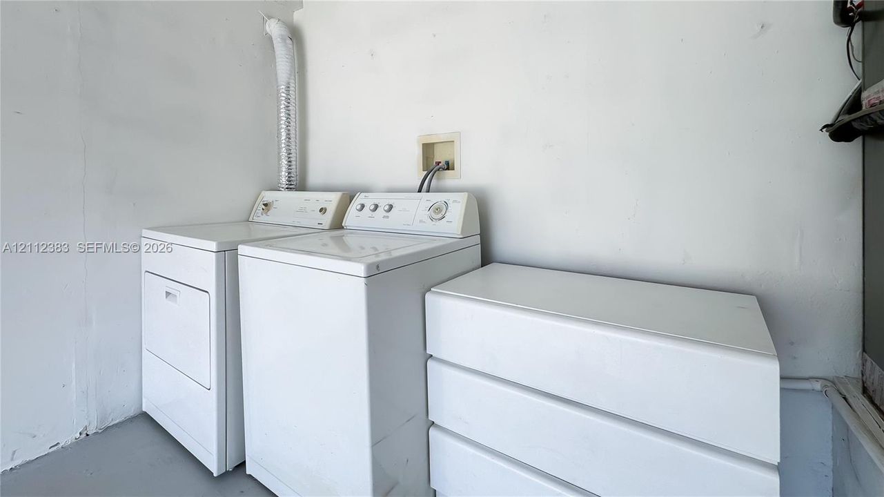Utility space featuring white laundry appliances and a built-in white storage unit