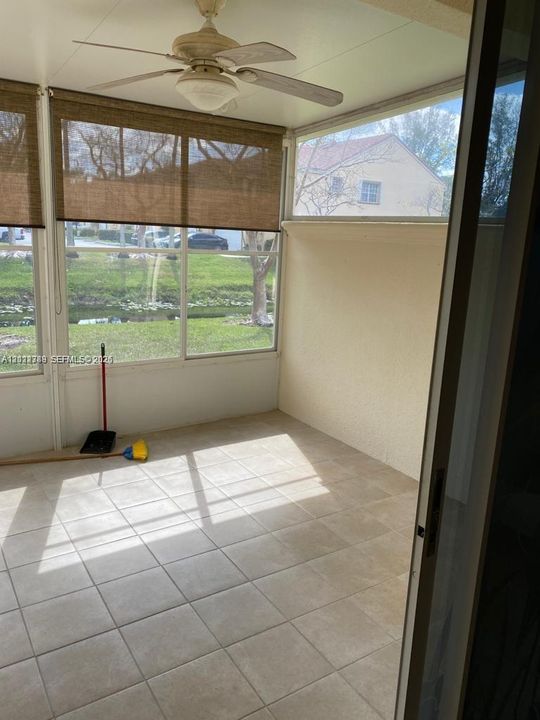 Enclosed patio featuring light-toned tile flooring, large windows, a ceiling fan, and privacy shades
