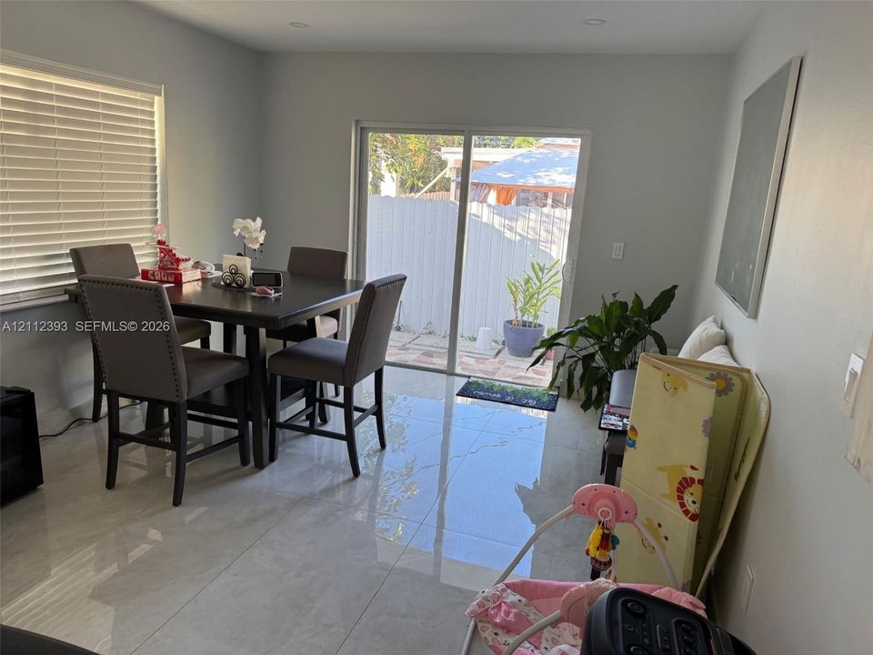 Large-format porcelain tile flooring, sliding glass door, recessed lighting, and horizontal window blinds