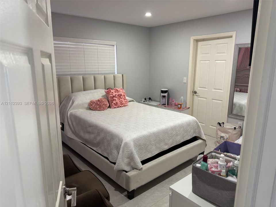 Neutral-toned interior featuring recessed lighting, a multi-panel interior door, and large-format tile flooring