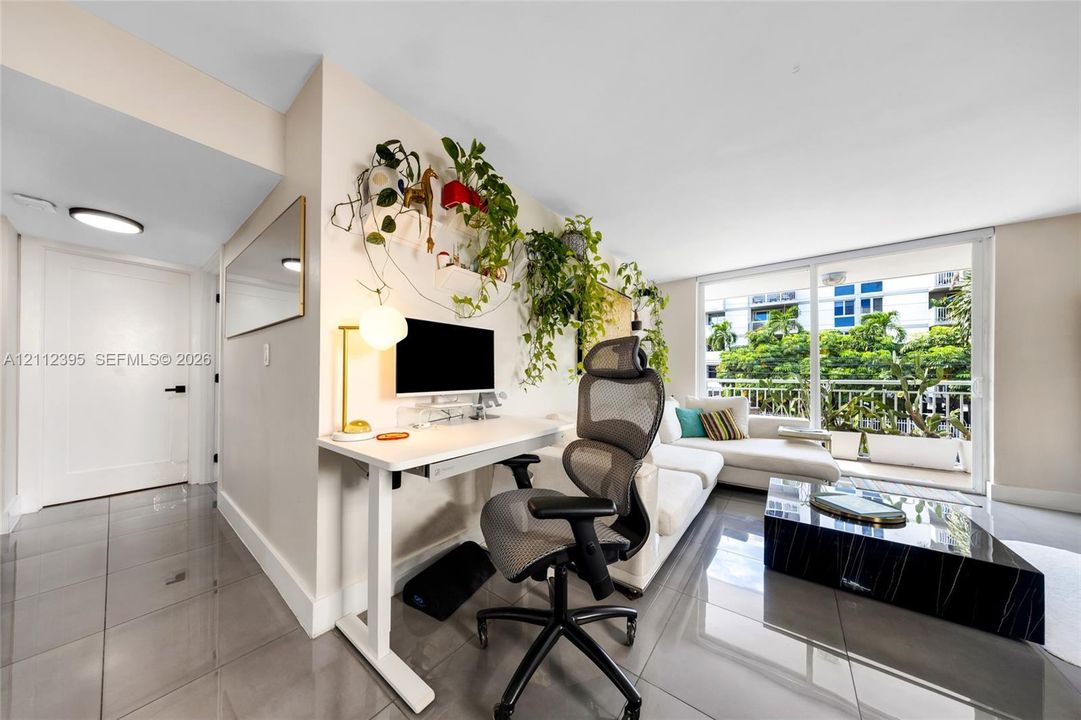 Large-format tile flooring, recessed ceiling lighting, and sliding glass door with access to a railed balcony