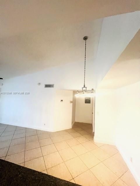 Vaulted ceiling featuring a multi-light pendant fixture and neutral tile flooring laid on a diagonal pattern