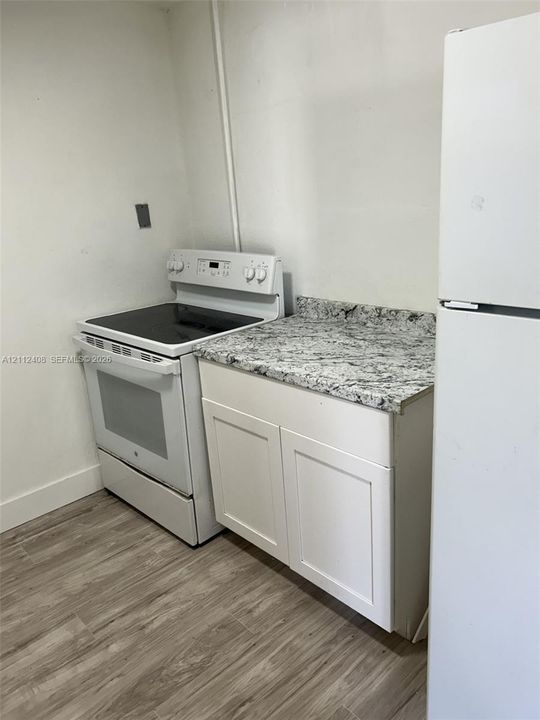Kitchen featuring white shaker-style cabinetry, stone-finish countertops, a freestanding electric range, and wood-finish flooring