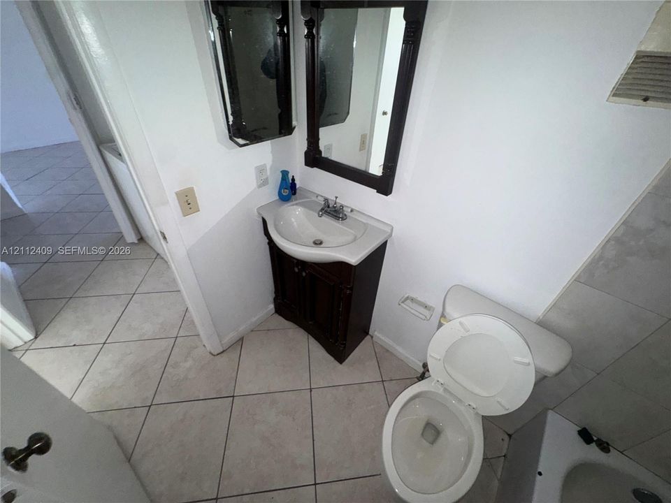 Single-sink vanity with dark wood-finish cabinetry, ceramic tile flooring, and wall-mounted mirror