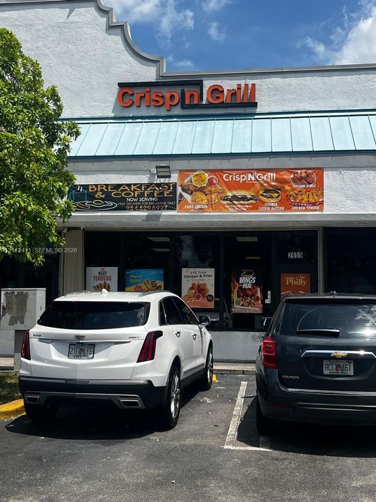 Commercial storefront featuring a stepped roofline, metal awning, glass-front entry, and dedicated parking space