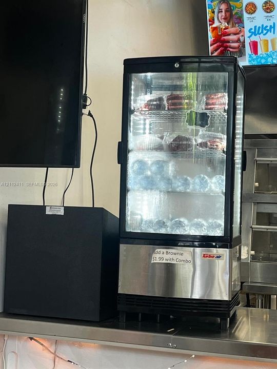 Countertop glass-front merchandiser refrigerator featuring a stainless steel base, interior LED illumination, and four adjustable display shelves
