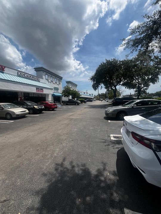 Commercial retail center featuring a paved parking lot with marked stalls, stucco exterior facade, decorative parapet details, and metal awnings